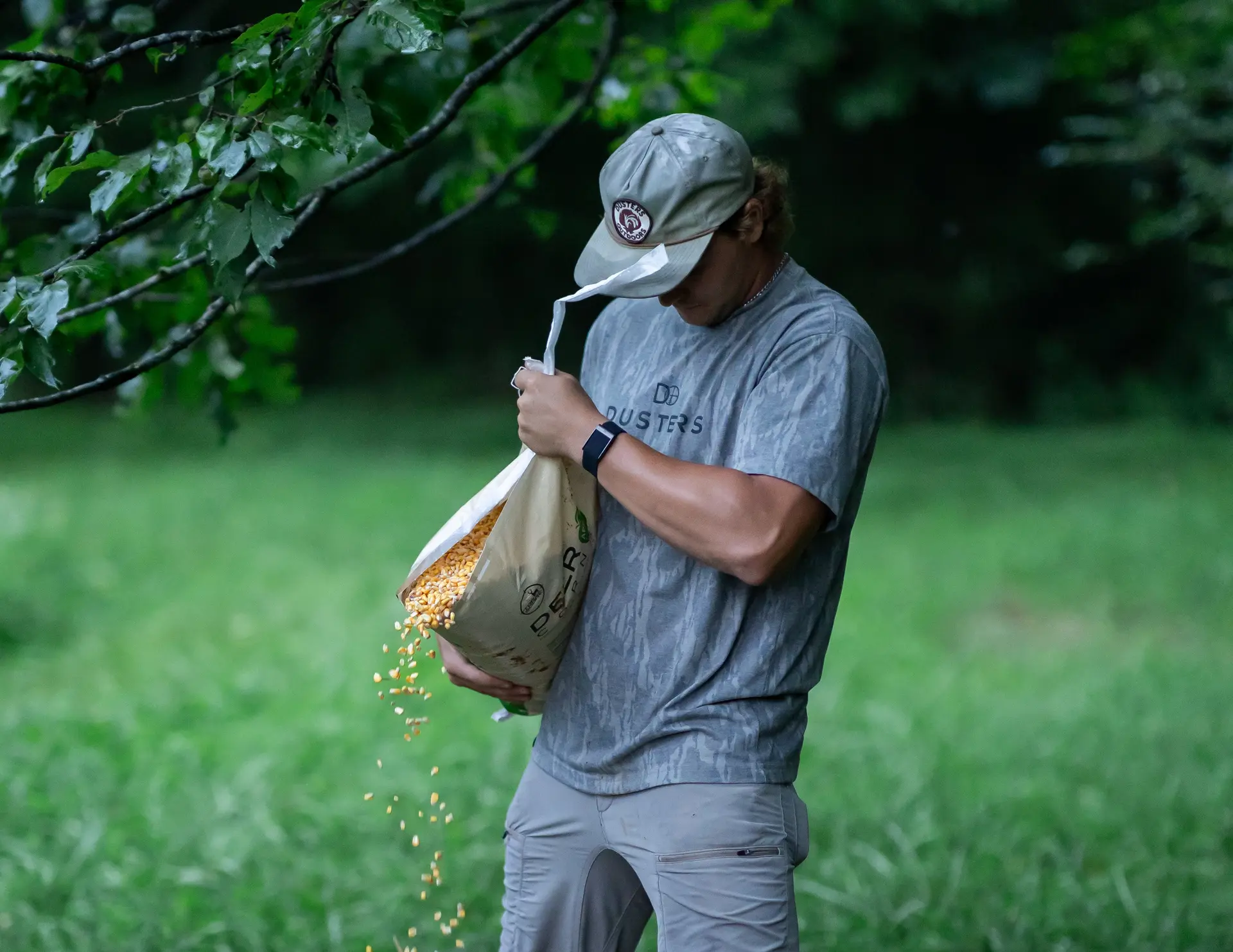 Dusters Outdoors team member filling a wildlife feeder in the field